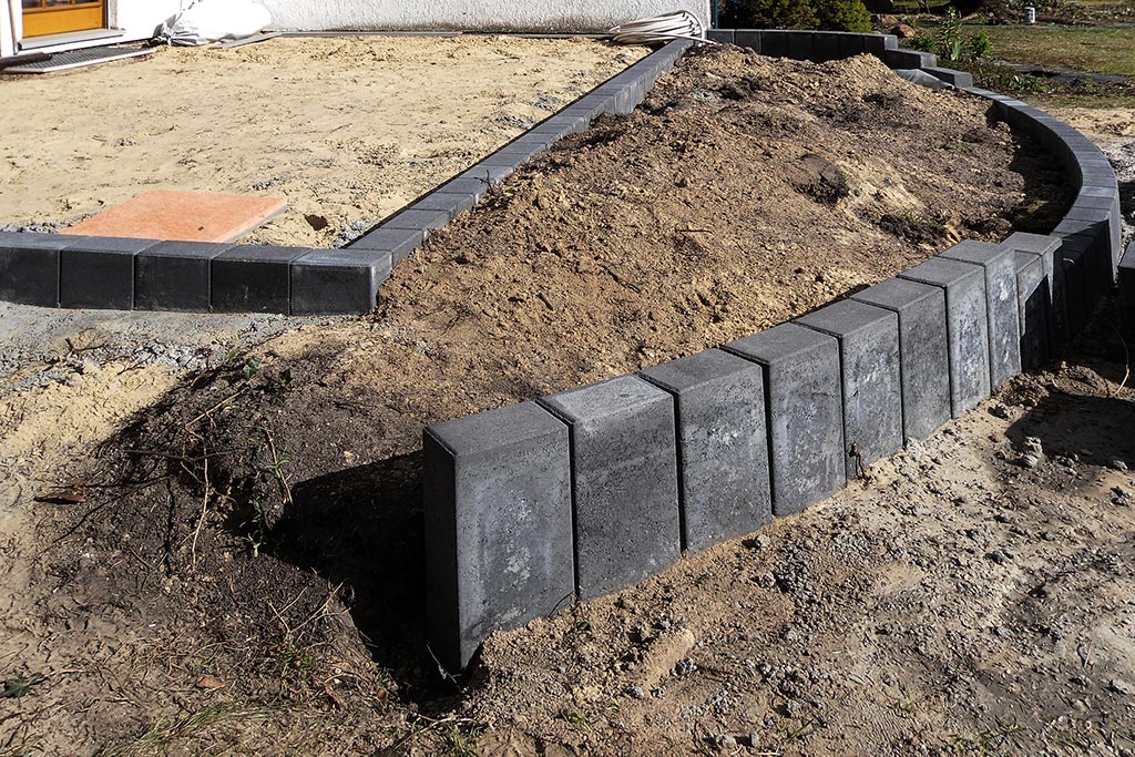 Terrassenneugestaltung: frisch gesetzte Einfassung aus viereckigen Betonpalisaden